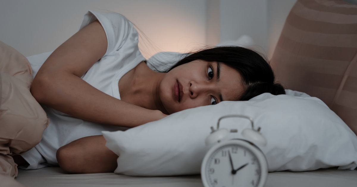 Frau im Bett mit Schlafproblemen, die um 2 Uhr morgens aufwacht, vermutlich aufgrund gestörten Cortisolwerten